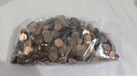 Plastic bag filled with approximately 980 pennies, a mix of Canadian and US coins in various conditions.
