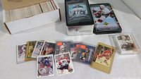 Photo showing a box filled with hockey cards and several displayed hockey cards from various NHL teams laid out next to it.