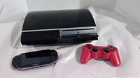 Full lot showing PS3 console, PS Vita, and red controller on white background