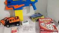 Various toys and games including a toy gun, model kit, Yahtzee game, yo-yos, toy car, playing cards, and a small toy van.