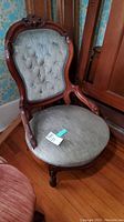 Front left angle view of the vintage chair showing carved wooden frame and tufted upholstered back