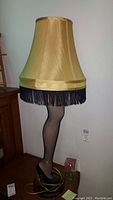 Full view of the leg lamp showing shade, fringe, fishnet stocking leg and high heel base