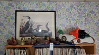 Wide shot of duck collectibles on shelf, showing framed print, wooden ducks, and duck clock.