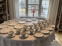 Wide shot of full china set arranged on a table with window background showing all pieces included in the lot.