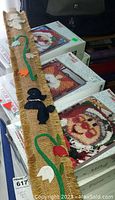 Photo of six boxed latch hook rug kits with colorful designs and a yardstick with fabric craft sheath.