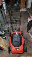 Front angled view of the Black & Decker Lawn Hog electric mower showing the orange body, black handle, and four wheels.
