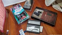 Photo of the toilet repair kit, armrest organizer, and gift pen box on wooden floor showing all three items together.