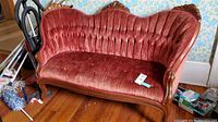 Front angle view showing carved wood frame detail and red velvet upholstery with wear.