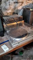 Sony PS-T22 turntable with transparent dust cover showing some wear and dust, stacked with Sylvania VHS player and stereo receiver underneath