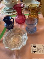 Overview of all glass and ceramic items in the lot on a table showing pitchers and candy dishes together.