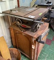 Beaver Power Tools table saw placed on a wooden base cabinet with visible handwheels and power cord.