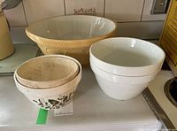 Group of all five ceramic bowls showing two with holly motif, two white bowls, and one large bowl.