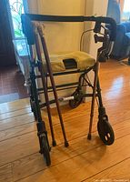 Front view of Evolution walker with 3 wooden canes leaning against it, showing padded seat and caster wheels.