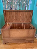 Cedar chest with open lid showing interior cedar lining and small internal storage compartment with key visible.