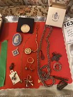 Tray view showing all jewelry pieces including chains, brooches, rings, charms and coin in box
