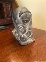 Front and side views of the Inuit soapstone carving showing the figure's facial detail and pose.