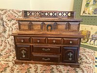 Photo showing the larger wooden jewelry box with lattice design on top lid and multiple drawers with metal knobs and handles