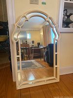 Full view of the decorative wood framed mirror showing the intricate top arch and side details, in indoor setting.