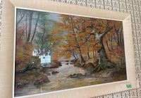 Framed painting on board illustrating a forest river scene with autumn colors and a large tree on the riverbank.