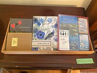 Overview photo showing six different boxes of playing cards and two boxed bridge games in wooden tray.