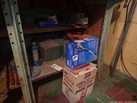 Shelf with metal toolboxes, spray canister, sandpaper rolls, and paint gun box.