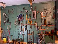 Wall-mounted pegboard showing a large assortment of hand tools including pliers, hammers, and clamps