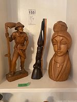 Three wooden carvings displayed together showing the size and detail.