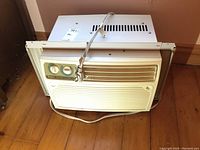 Front view of the white Gree window air conditioner unit sitting on the floor, showing vents and control panel area.