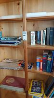 Wide view of multiple shelves containing stacks of books, folded maps, and magazines including visible titles like dictionaries and home reno books.
