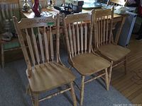 Three chairs side by side showing front view, spindled back and carved top rail