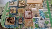 Overview of entire lot showing multiple small boxes filled with assorted costume jewelry including necklaces, earrings, brooches, and bracelets arranged on a floral tablecloth.