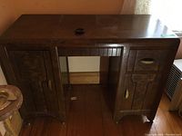Front view of vintage wood desk showing overall shape, top surface, one drawer and two cabinet doors