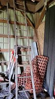 Tall wooden ladder leaning against a barn wall with other barn materials visible around it