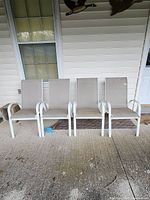 Four patio chairs lined up on a porch showing general condition, frame, and seating material.