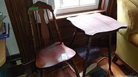Photo showing vintage wooden chair and table next to a window and sofa, highlighting the chair's spindle back and the table's scalloped top.