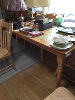 Side view of wooden dining table with items on top (not included). The table surface is smooth and light wood tone.