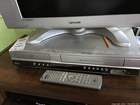 Full view of LG VHS/DVD player combo with remote control placed on top of it.