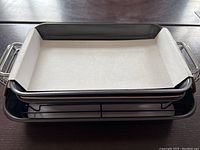 Top view on table showing three small rectangular non-stick metal baking dishes stacked with baking paper inside the top dish.
