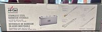 Box front showing All-Clad Metalcrafters branding and graphics depicting the 4-piece stainless steel BBQ utensil set with carrying case.
