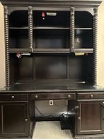 Front view of the full desk with storage hutch showing the upper shelves, decorative twisting columns, drawers, and lower cabinets.