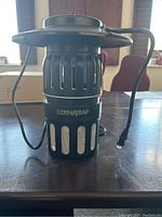 Photo of DynaTrap bug zapper showing front and power cord on table.