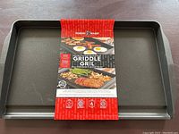 Full view of the double burner griddle with packaging showing it is new and heavy cast aluminum.