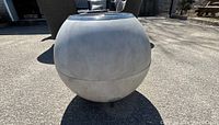 Front view of spherical concrete fire pit on pavement