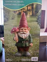 Box showing full-color image of garden gnome holding a mushroom, standing on grass, labeled in multiple languages.