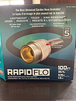 Front view of the new box of Rapid Flo garden hose showing product features, length 100ft, diameter 5/8 inch, 5 year warranty.