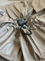 Deflated taupe inflatable hot tub laid out with AirJet pump and hoses