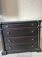 Front view of solid wood office credenza showing three dark wood drawers and twisted wood columns on sides.
