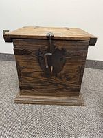 Front view of small wooden trunk showing wood grain, metal lock plate and latch