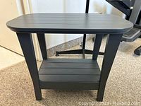 Front view of grey patio side table showing the slatted top surface, sturdy legs and lower shelf.