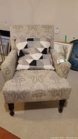 Front view of the fabric arm chair with patterned upholstery and a geometric patterned cushion on the seat.